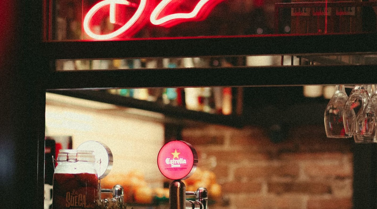 Warm-lit cocktail bar interior with neon sign