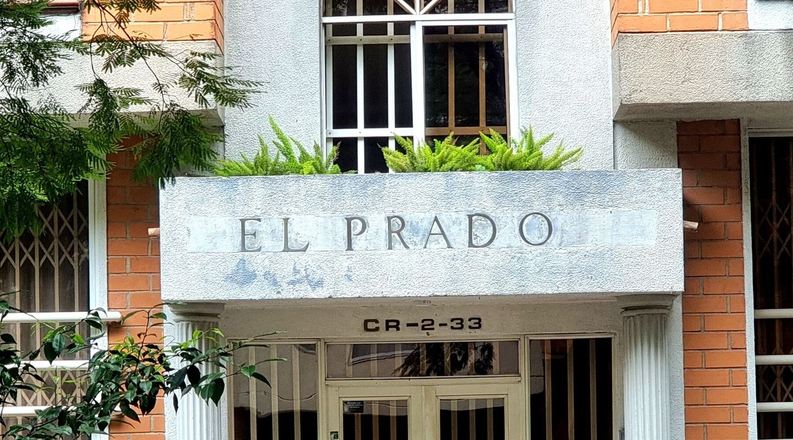 A brick building entrance with planters on a quiet El Poblado street