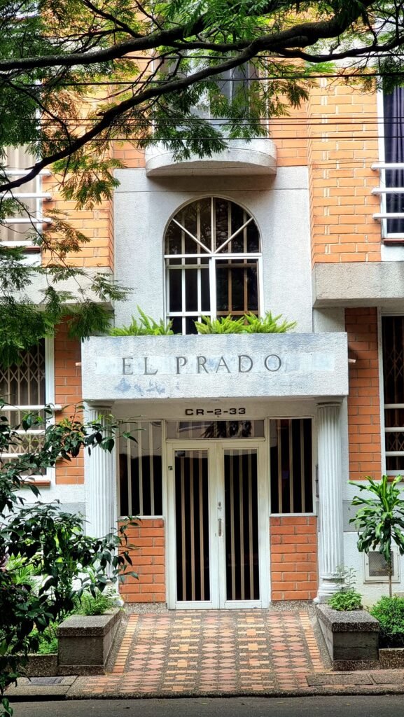 A brick building entrance with planters on a quiet El Poblado street