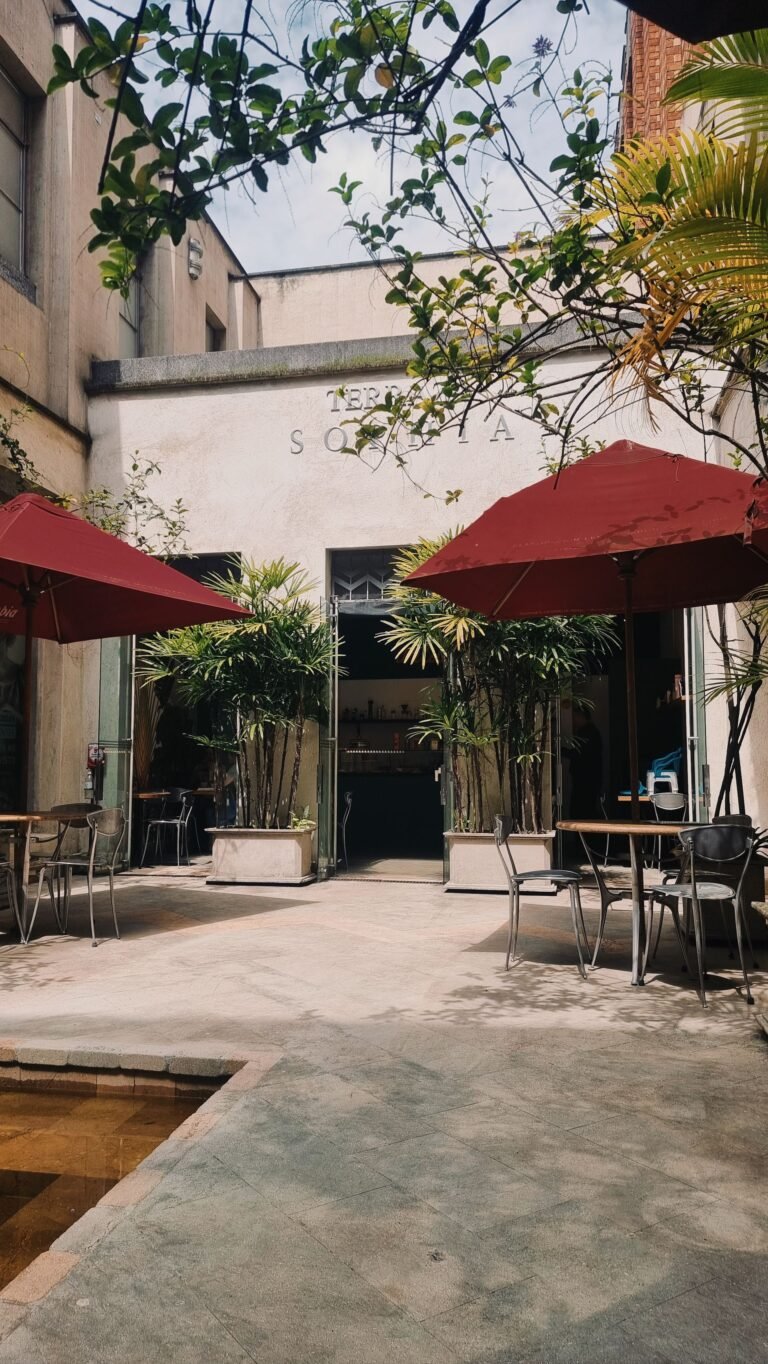 Outdoor café terrace with umbrellas on a tree-lined street in Medellín