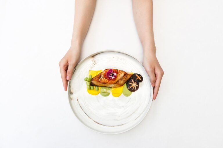 A small plated gourmet dish garnished with mushrooms and an edible flower