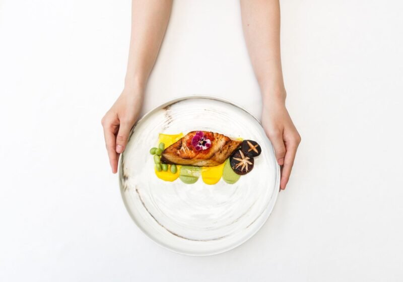 A small plated gourmet dish garnished with mushrooms and an edible flower