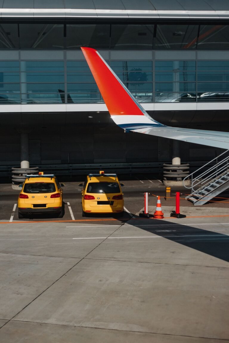 Yellow taxis waiting outside an airport terminal beside a parked aircraft